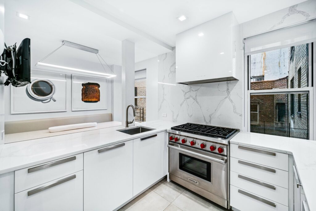 Renovated kitchen, with white cabinets, stainless steel appliances, white range hood