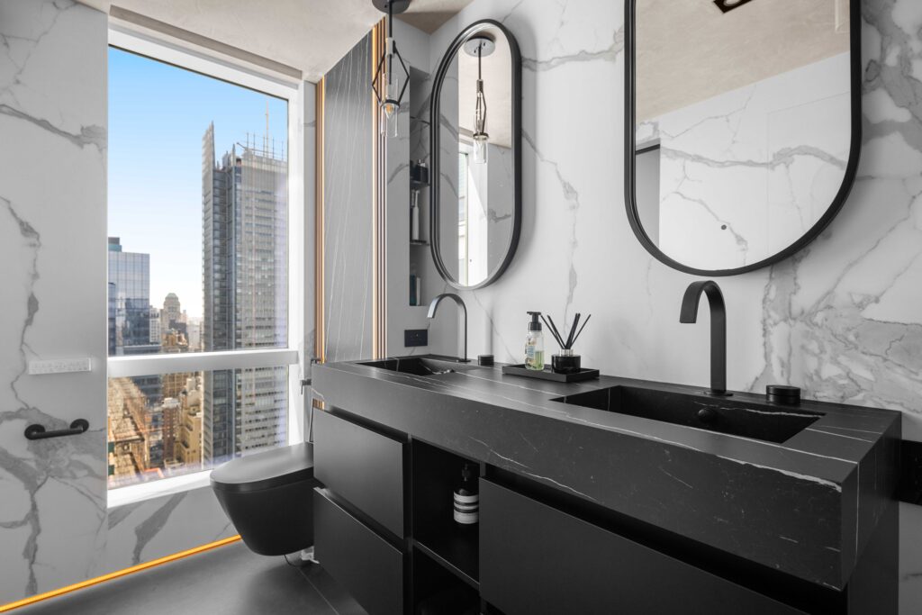 Luxury NYC bathroom, with black marble floating vanity, two rounded glasses, black toilet and white wall tiles