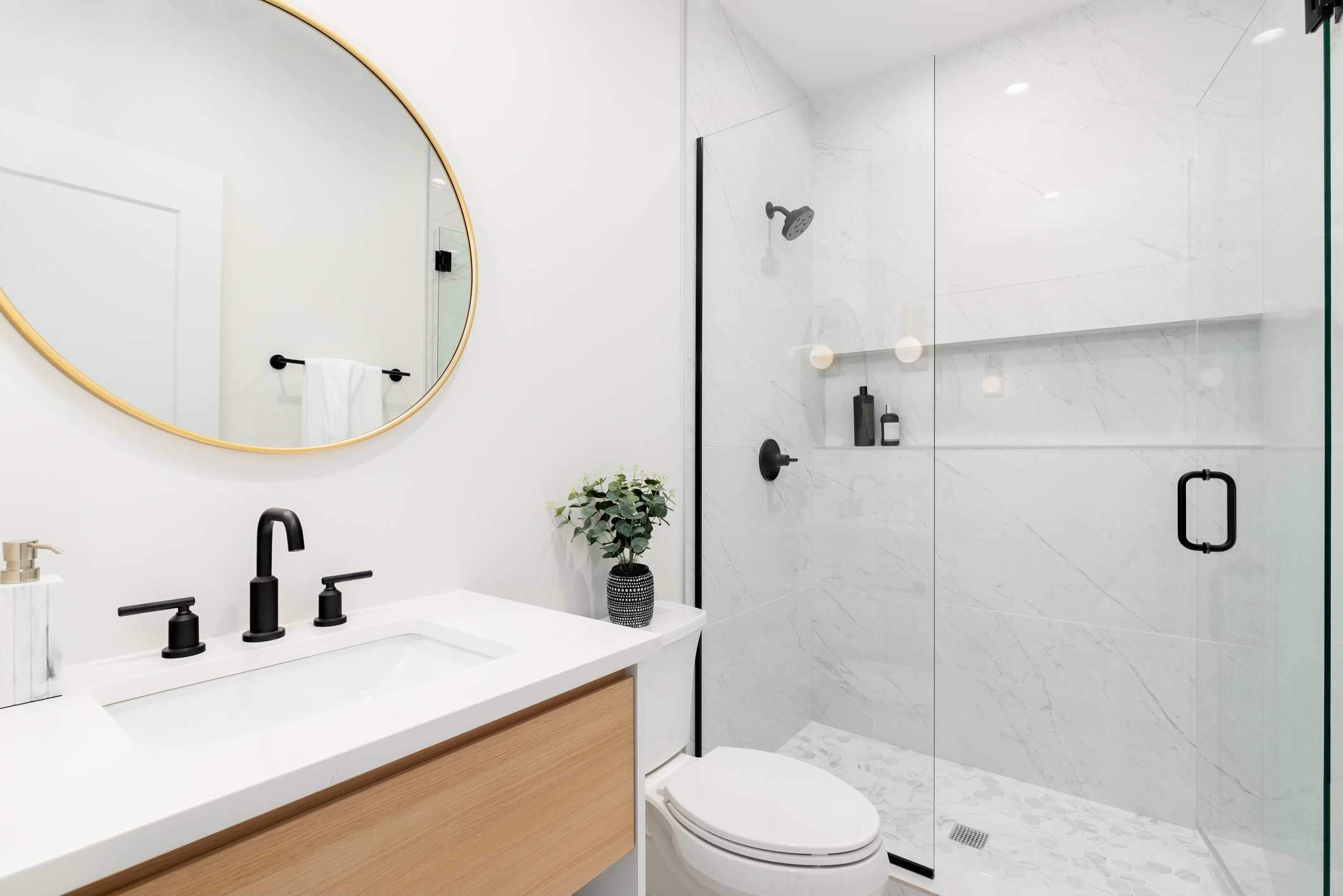 From tub to shower, white shower, with white tiles and floating brown vanity, round mirror on top