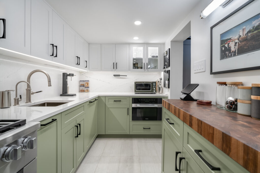 Renovated kitchen, green bottom and white top cabinetry, sleek appliances, wooden toned bar