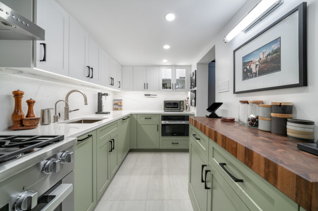 Remodeled kitchen with green and white cabinets, wooden tones and stainless steel appliances