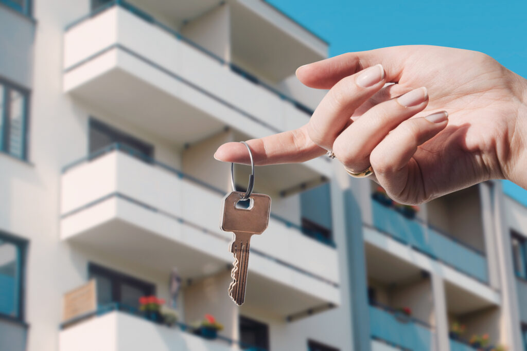 person holding keys before selling apartment in front of the white building