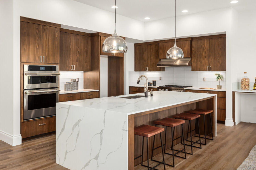 Renvoated kitchen with white countertop, chandeliers and brown cabinetry