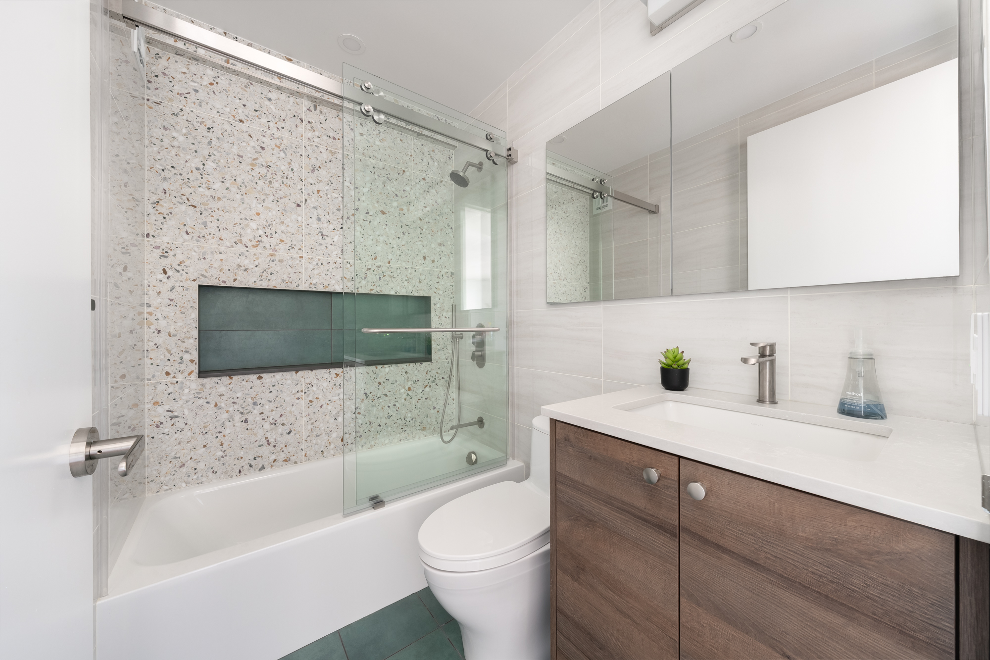 Renovated full apartment in NYC, bathroom features green tiles, green tiled bathroom niche and wood toned vanity