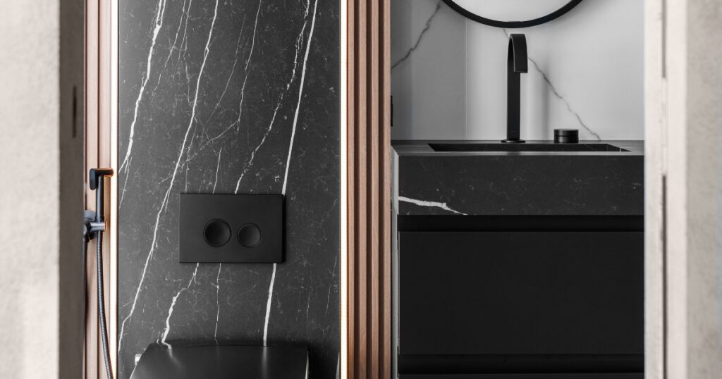 Modern Klein Kitchen and Bath bathroom renovation with black marble-look tile, black vanity, wall-mounted faucet, and matte black fixtures