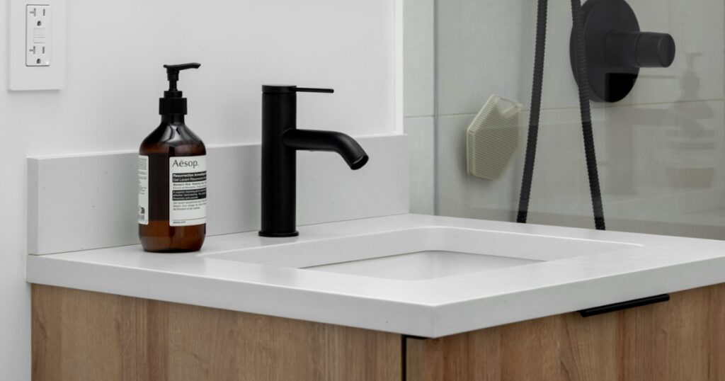 Klein Kitchen and Bath bathroom vanity featuring a white quartz countertop, wood cabinet, and matte black faucet