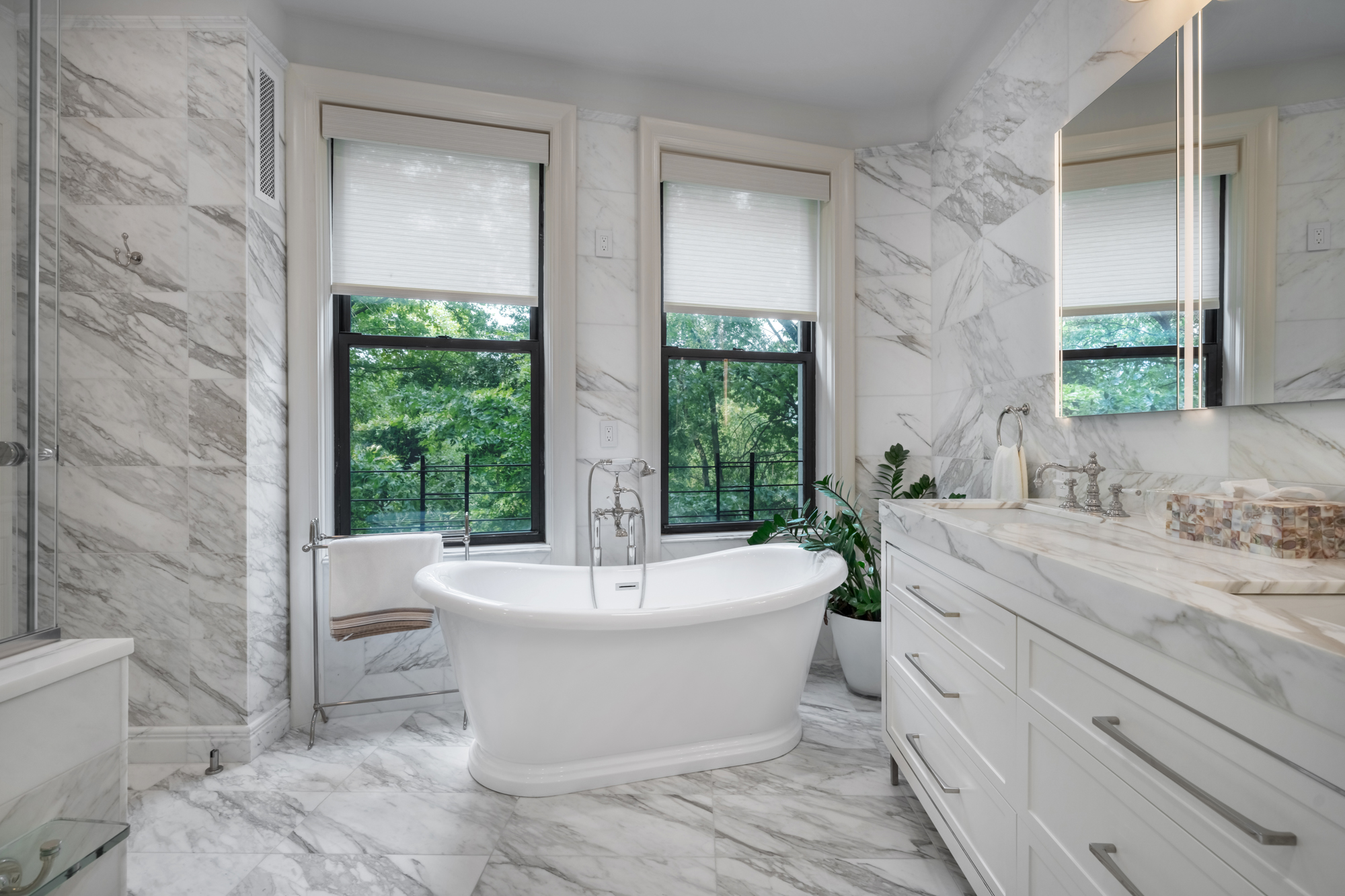 A bright Riverside Drive bathroom remodeled by Klein Kitchen & Bath with marble finishes, a freestanding tub and custom vanity.