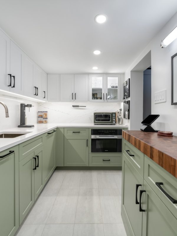 Remodeled kitchen with green and white cabinets, wooden tones and stainless steel appliances