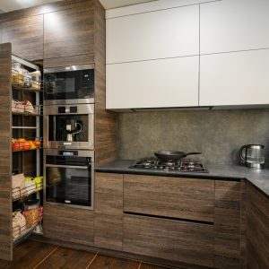 Modern large luxurious dark brown, gray and black cozy kitchen interior, big vertical drawer pulled out