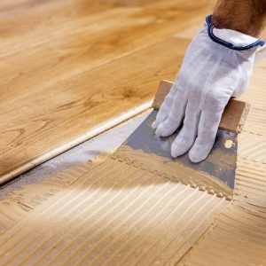 worker apply adhesive for 3 layer parquet flooring