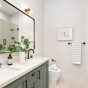 Modern bathroom interior with dual sinks, large mirror, and elegant decor in a bright setting.